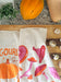 Gourd and mushroom towels photographed with rosemary, gourds, and mushrooms on a kitchen counter and cutting board