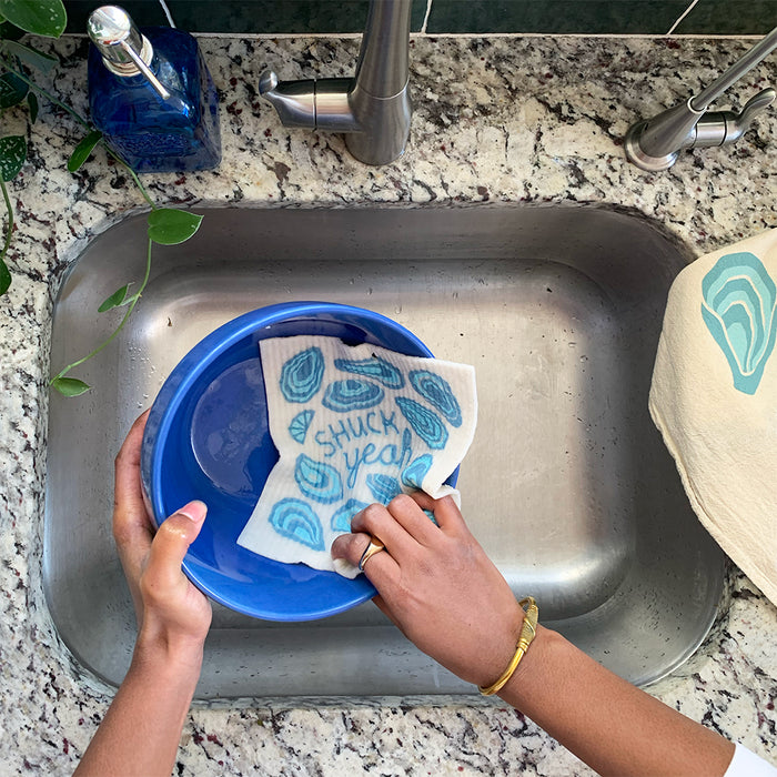 A woman washes a bowl with a oyster sponge cloth.