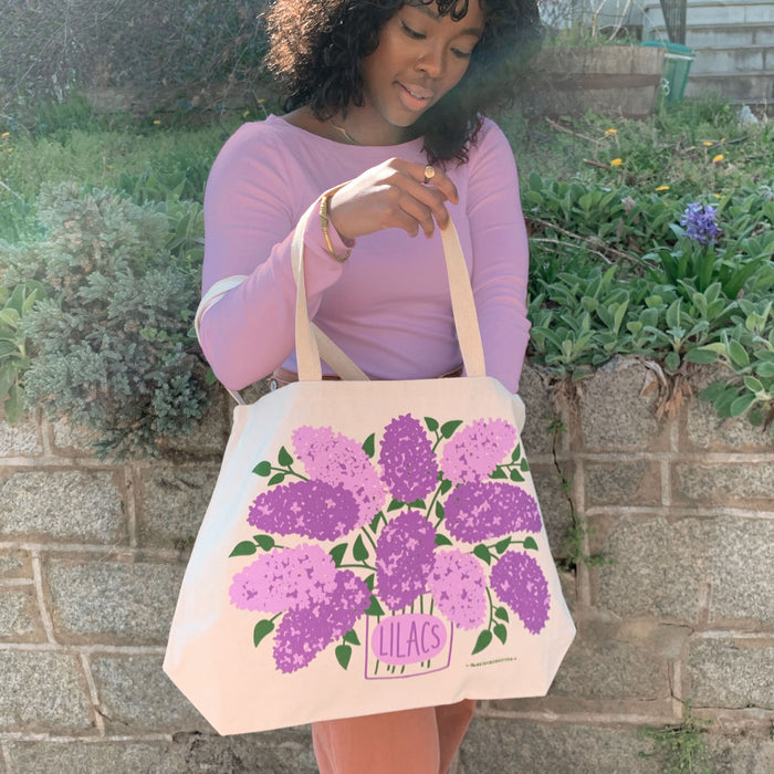 A woman reaches inside the Lilac tote bag.