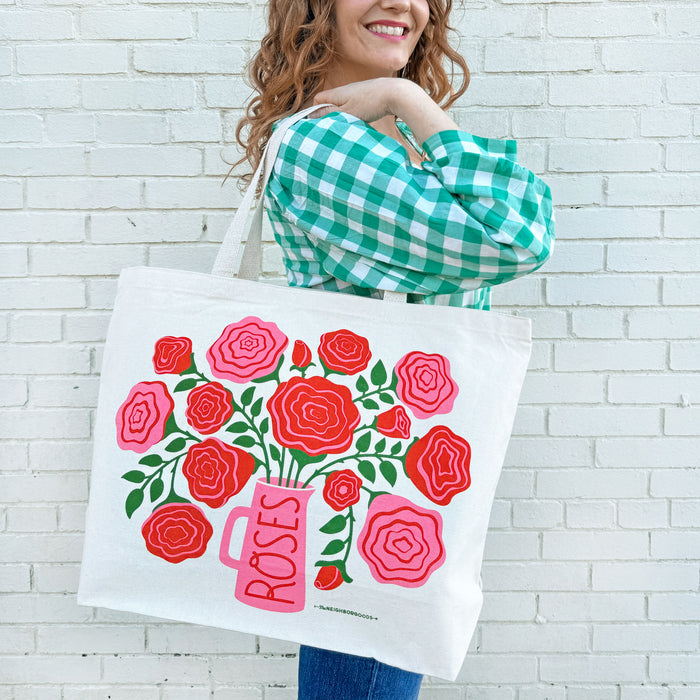A woman carries a Roses tote bag on her shoulder.