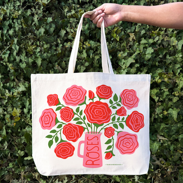 A woman holds a Roses tote bag on her shoulder.