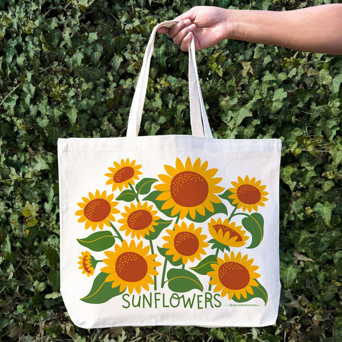 A woman holding The Neighborgoods Sunflowers tote bag.