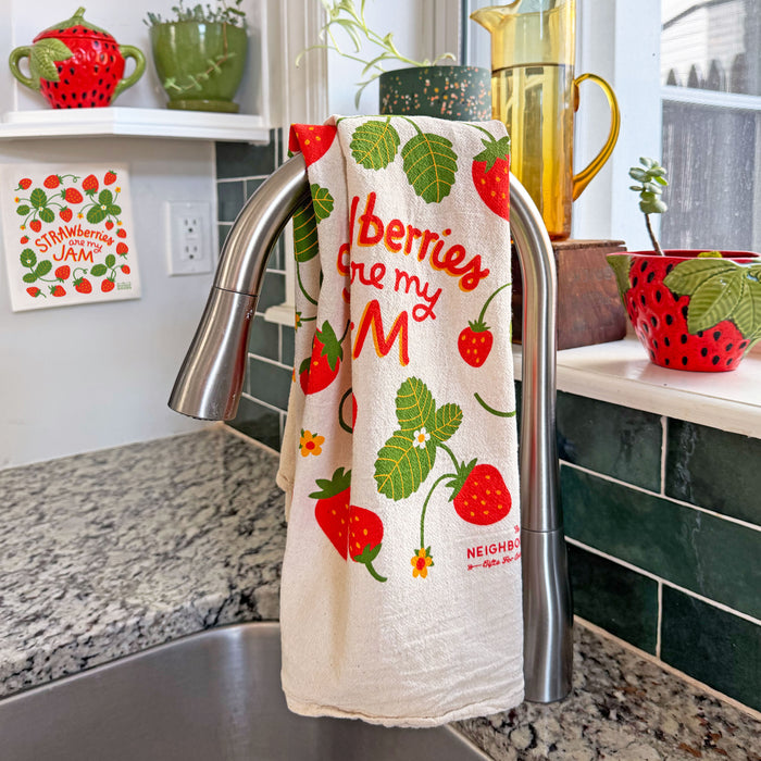 Strawberry dish towel hanging over a kitchen sink faucet.