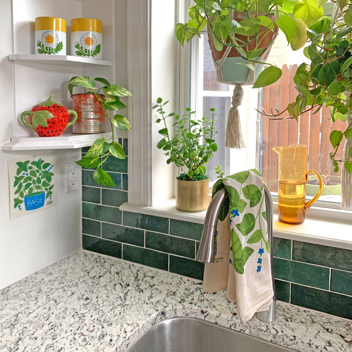 basil dish towel draped over sink faucet