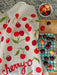Cherry dish towel on a kitchen counter and cutting board with cherries