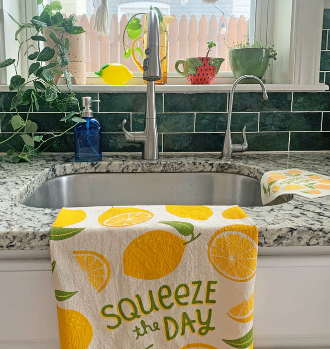The Neighborgoods Lemon dish towel with a lemon food pun illustration hanging over a counter.