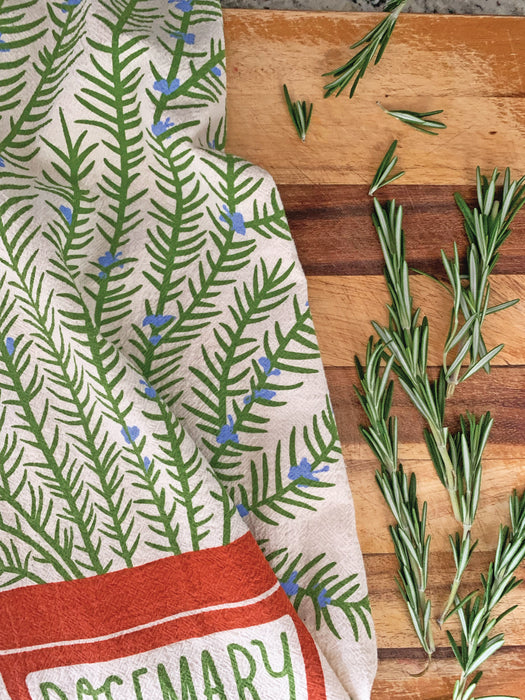 Rosemary screen-printed kitchen dish towel on cutting board next to rosemary shrubs