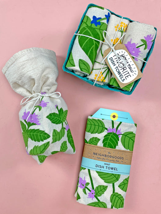 Fresh herbs dish towel set photographed alongside packaged mint dish towel and a small gift wrapped in a mint dish towel