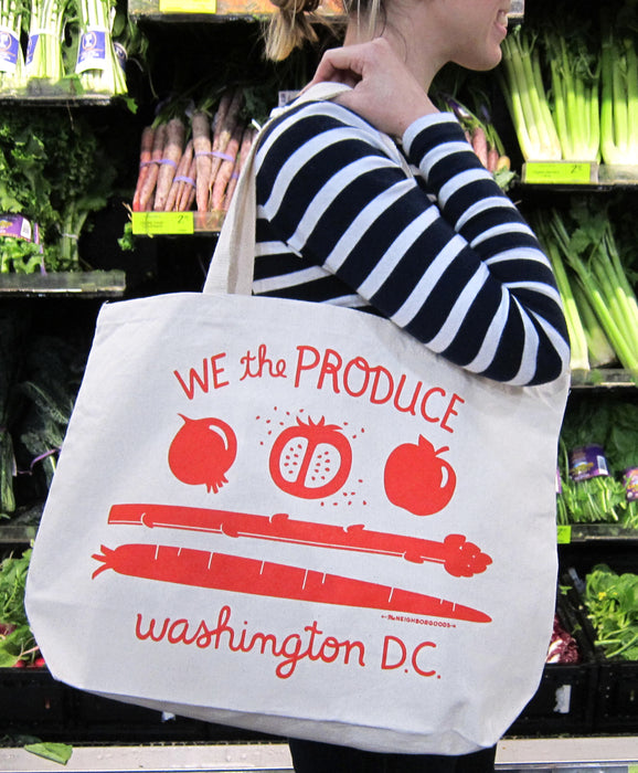 Person in a striped shirt carrying We the Produce tote in a grocery store