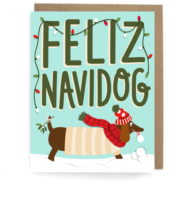 Pale blue card that pictures a dachshund dressed in a holiday outfit playiing in snow, featuring the phrase "Feliz Navidog," with a brown envelope
