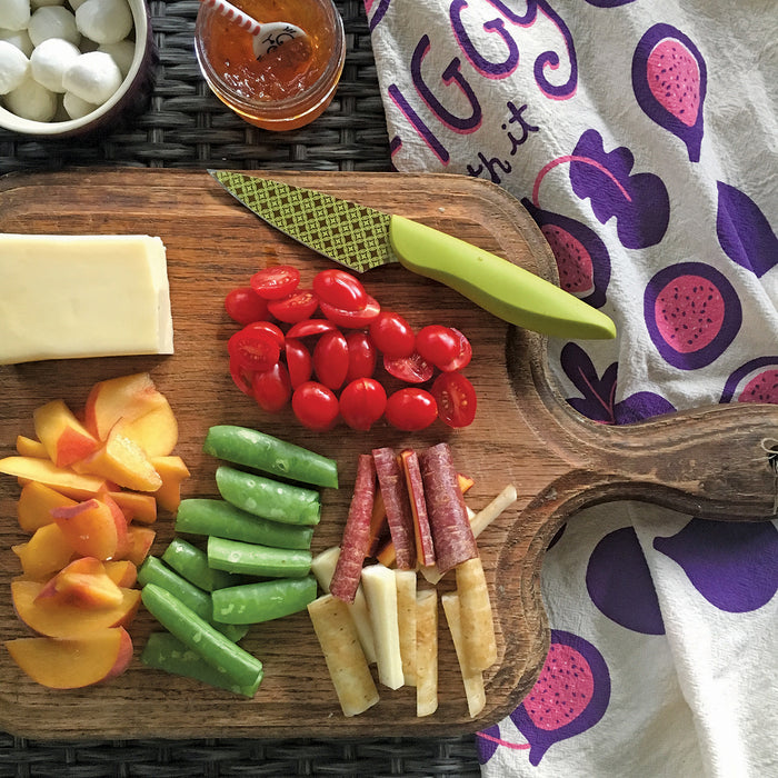 A cheese plate next to Get Figgy With It dish towel