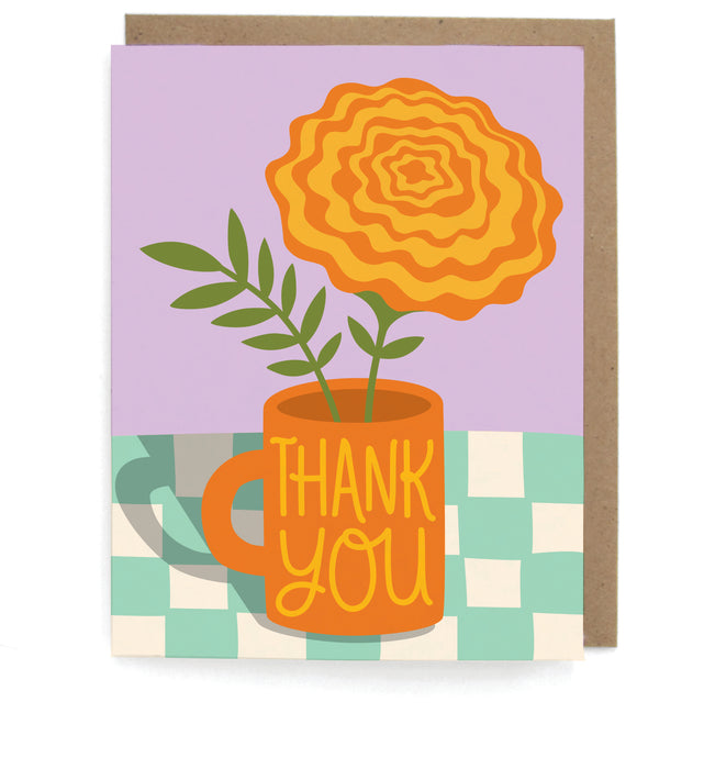 Card that pictures a marigold in a mug that says "Thank you" on a checkboard table, with a brown envelope