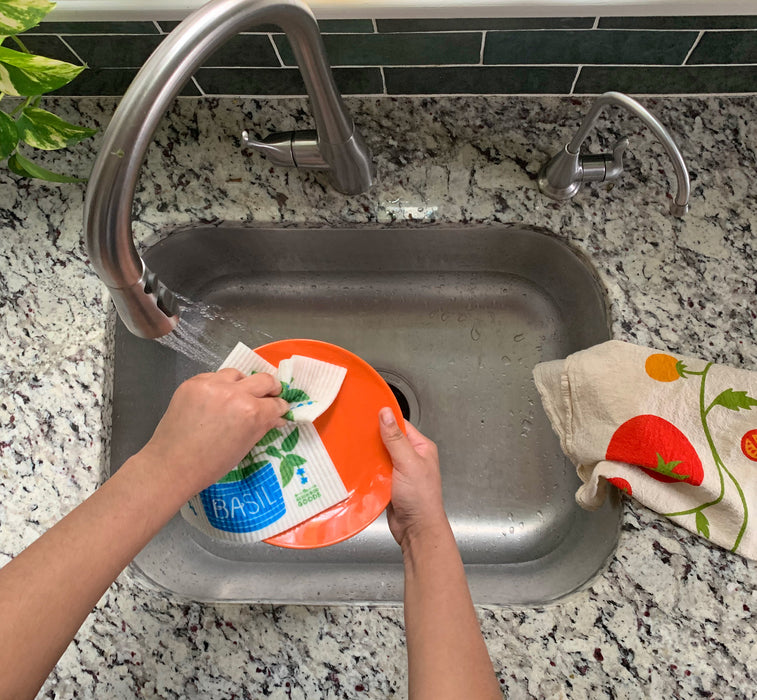 Basil sponge cloth being used to clean dishes in a sink