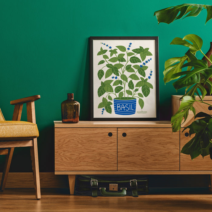 Basil print in medium size framed on a stand next to a chair and plant
