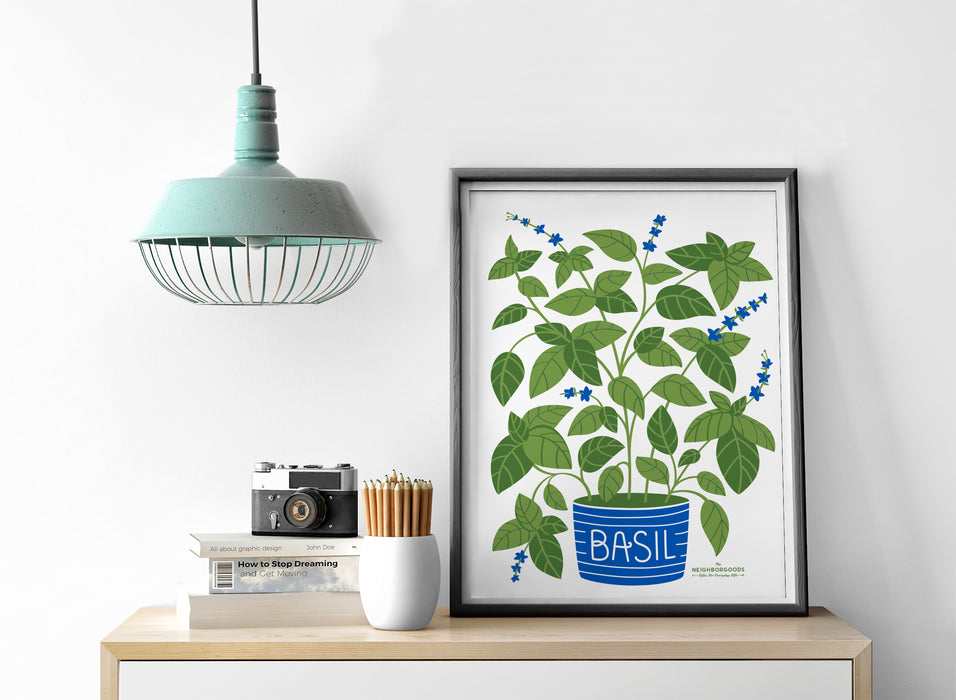 Basil print in medium size alongside light, camera, pencils, and books