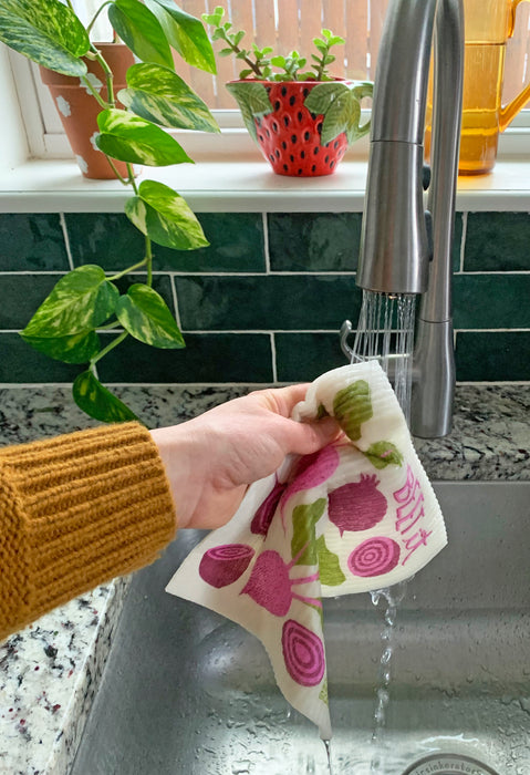 Beet sponge cloth being put under running water in a sink