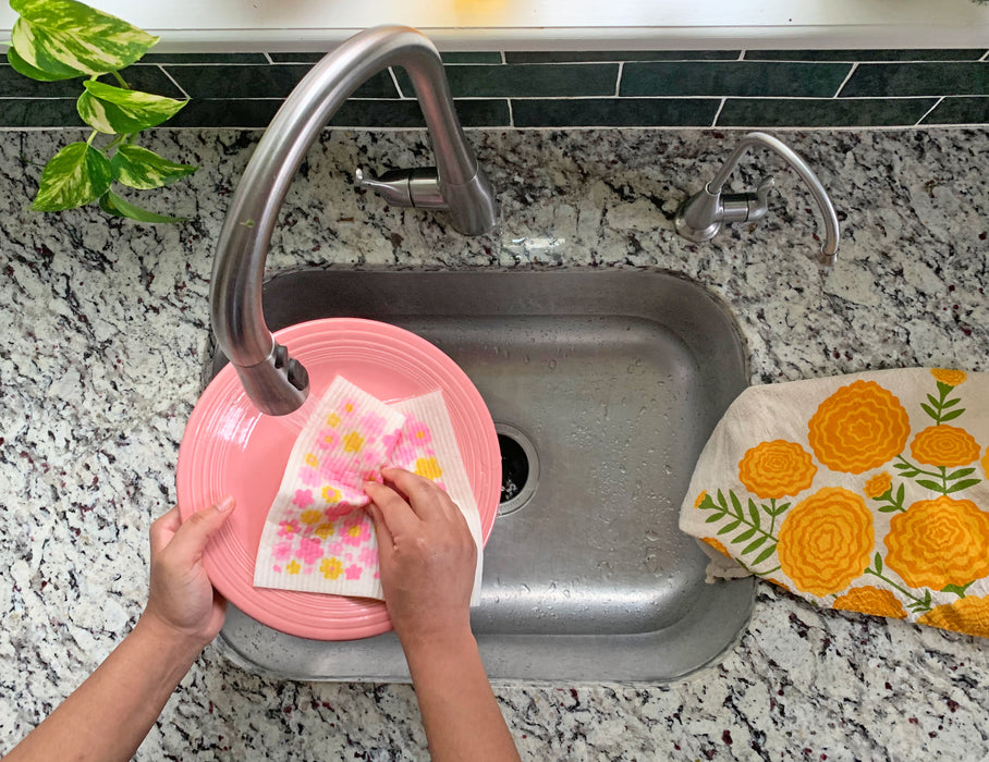 Blossom sponge cloth being used to clean dishes in a sink