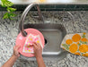 Blossom sponge cloth being used to clean dishes in a sink