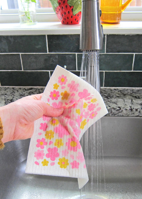 Blossom sponge cloth being put under running water in a sink
