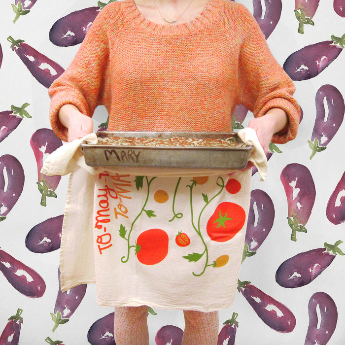 Person carrying casserole dish with tomato dish towel