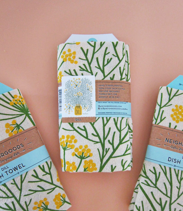 Back view of three packaged Dill dish towels folded in branded belly band sleeves. Packaging includes product image and info.