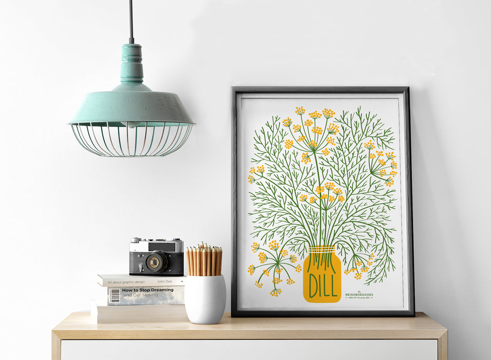 Dill print in medium size alongside light, camera, pencils, and books