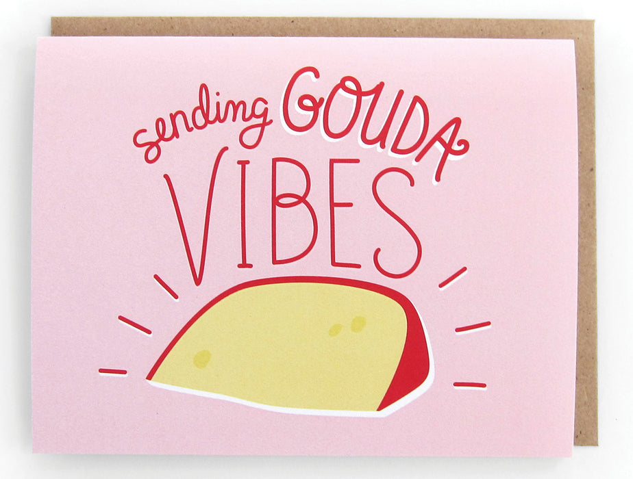 Pale pink card that pictures a wedge of gouda cheese, featuring the phrase "Sending gouda vibes," with a brown envelope