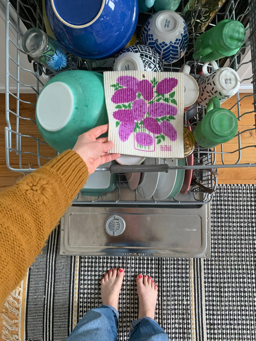 Lilac sponge cloth placed in the top rack of a dishwasher to be cleaned