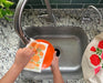 Marigold sponge cloth being used to clean dishes in a sink