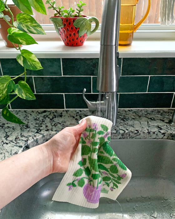Mint sponge cloth being put under running water in a sink