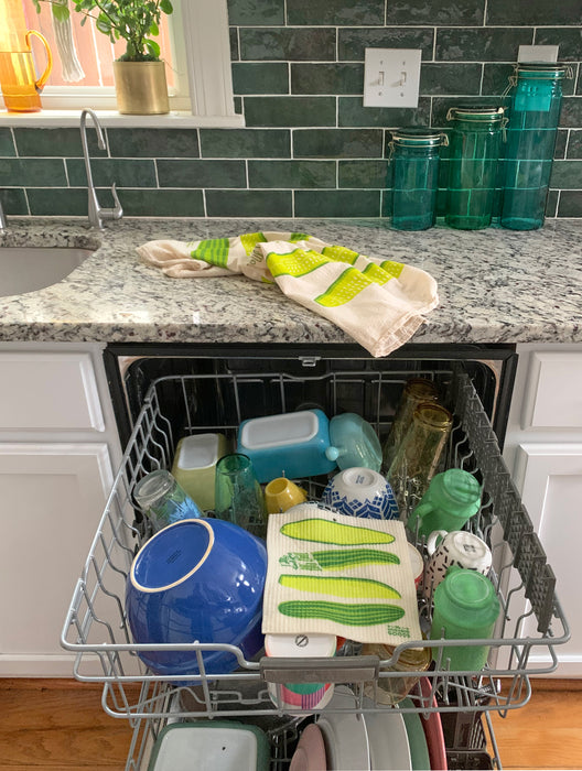 A pickle sponge cloth placed on the top rack of a dishwasher.