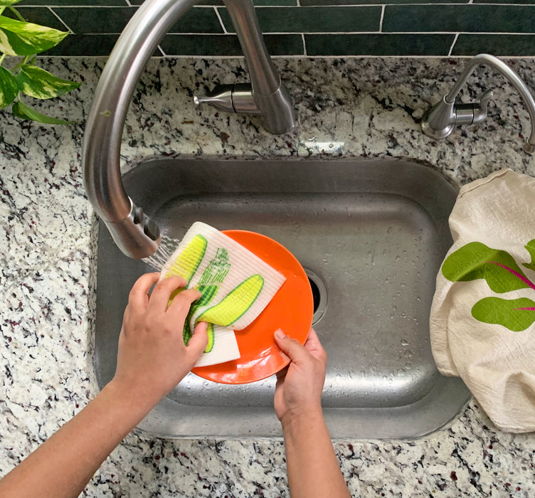 Pickles sponge cloth being used to clean dishes in a sink
