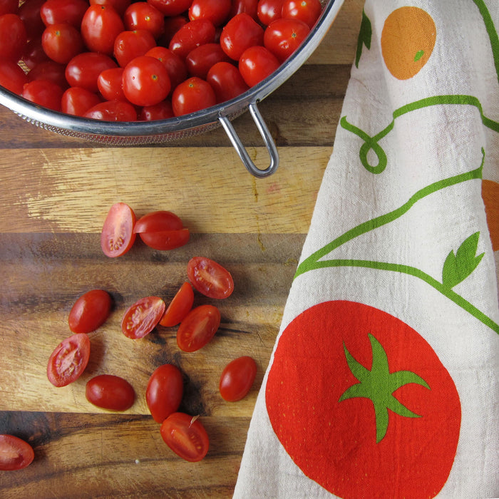 Tomato dish towel on cutting board with grape tomatoes