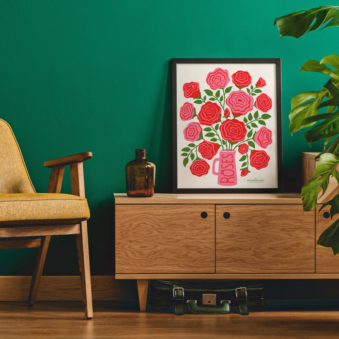 Roses print in medium size framed on a stand next to a chair and plant