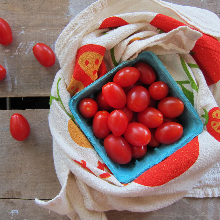 Tomato dish towel and grape tomatoes in produce carton