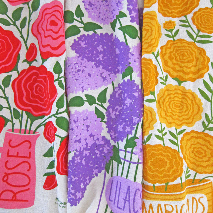 A gift set of three dish towels designed with illustrations of edible flowers.