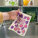 A fig sponge cloth becomes wet under running sink faucet.