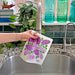 A lilacs sponge cloth becomes wet under running kitchen faucet.