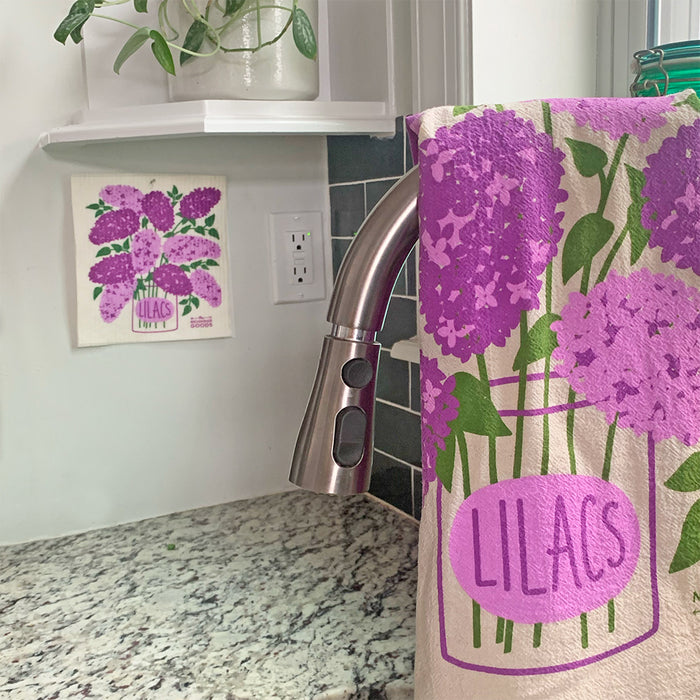 A lilacs sponge cloth and matching dish towel hanging in the kitchen.