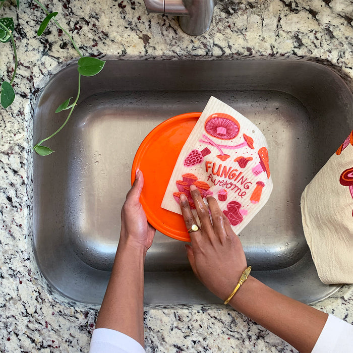 A woman washes a plate with the mushroom sponge cloth.