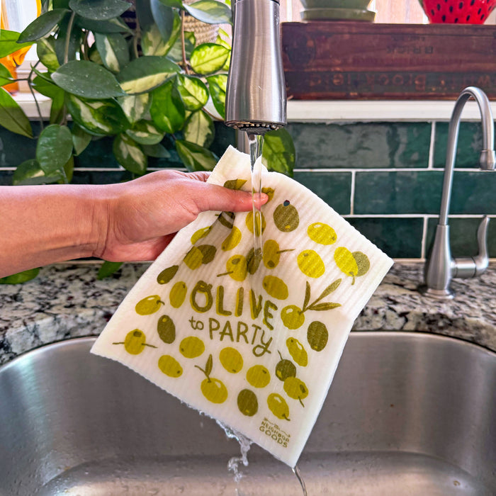 An olive sponge cloth becomes wet under the kitchen sink faucet.