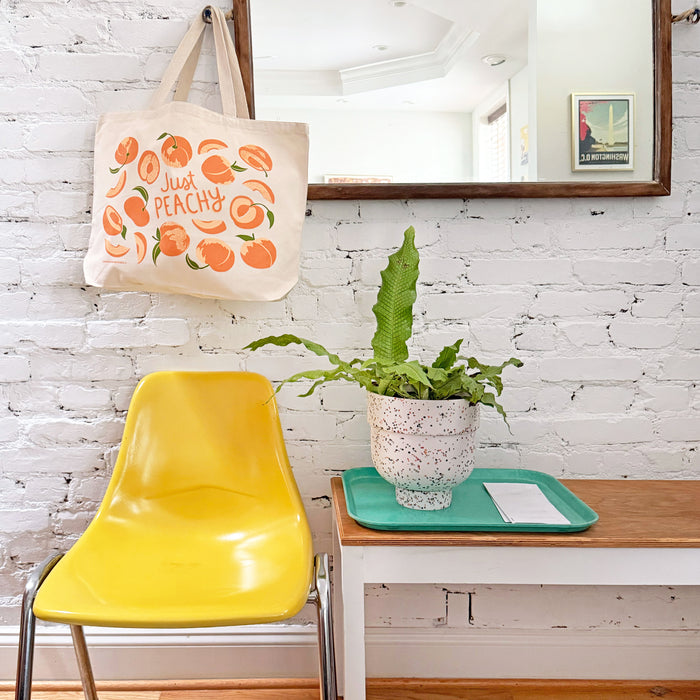 Peach tote bag hangs on a mirror hook.
