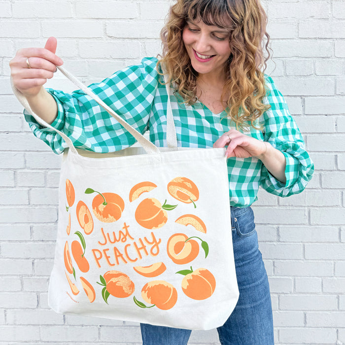 A woman opens and looks inside the oversized peach tote bag.