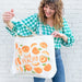 A woman opens and looks inside the oversized peach tote bag.