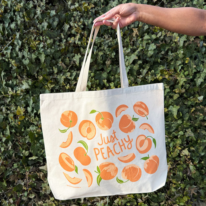 A woman holds a peach tote bag.