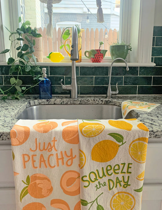 Peach and lemon dish towels folded over kitchen sink