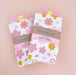 Two Cherry Blossom towel souvenirs. Both towels are packaged in The Neighborgoods branded belly band.