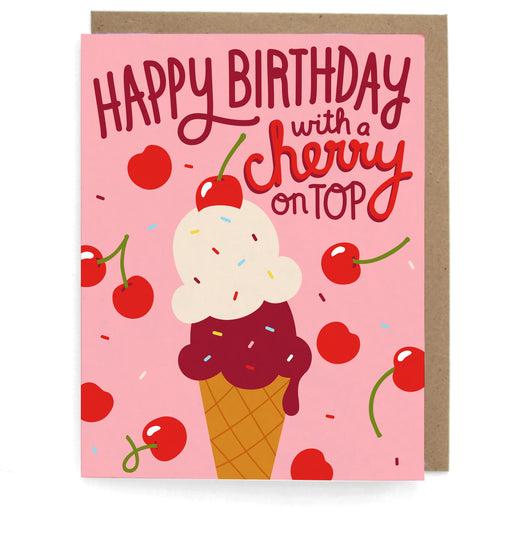 Pink card with an ice cream and cherries design, featuring the phrase "Happy birthday with a cherry on top," with a brown envelope