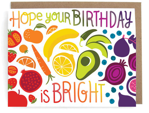 White card that pictures a rainbow of fruit and veggie designs, featuring the phrase "Hope your birthday is bright," with a brown envelope