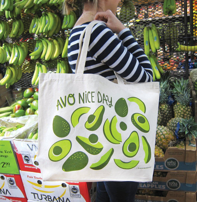 Person in a striped shirt carrying the avocado tote bag at the grocery store